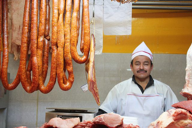 Carnicero en su mostrador con chorizos colgados